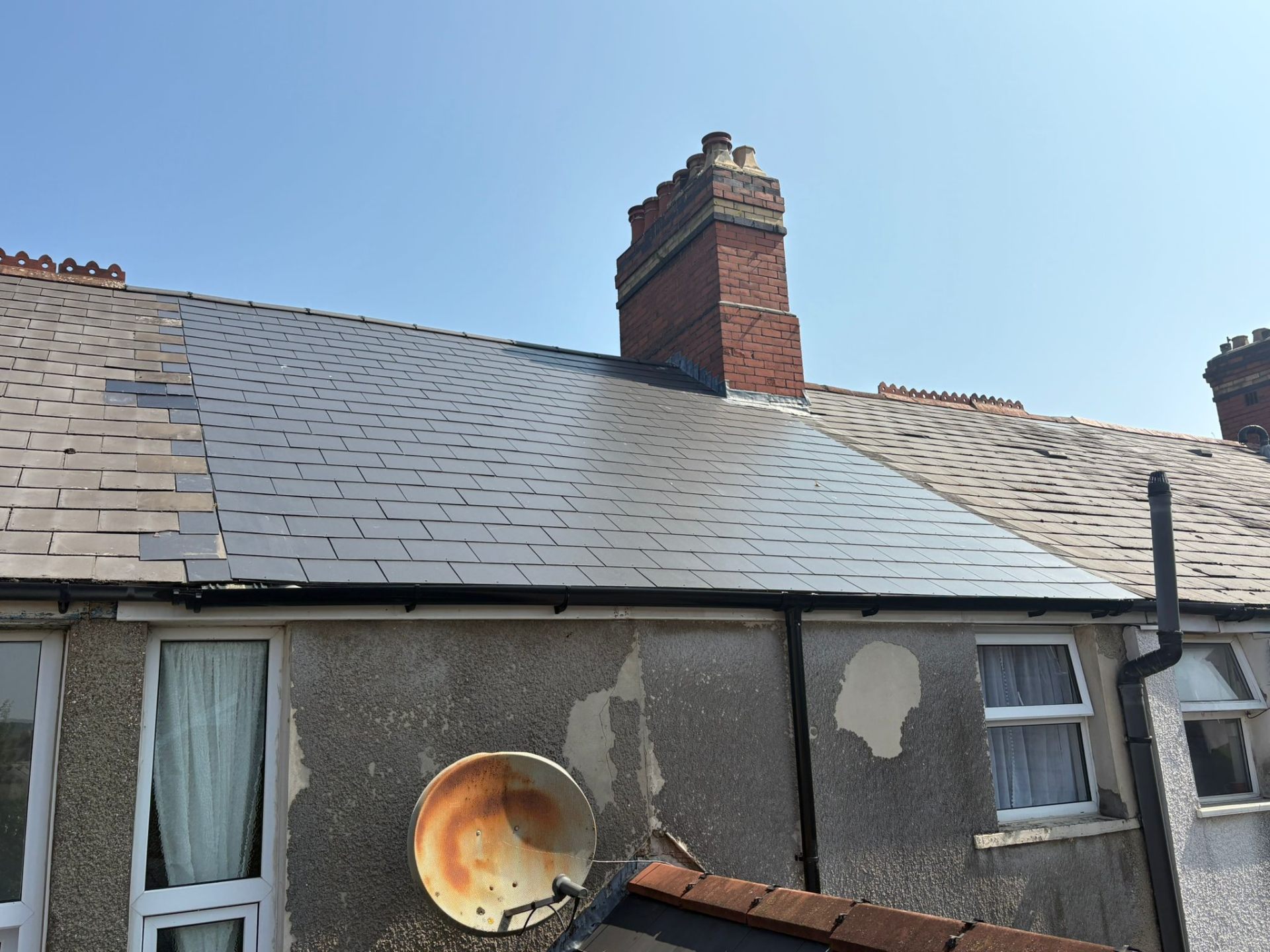 Completed slate re-roof showing new and existing slates on a terraced property